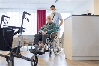 Carer with man in wheelchair in nursing home