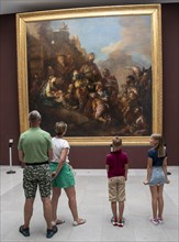 Tourists looking at a painting in the Louvre Museum