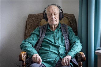 Old man in nursing home listening to music with headphones. Old man in nursing home listening to music with headphones.