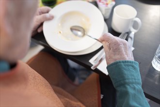 Old man in a nursing home spooning soup