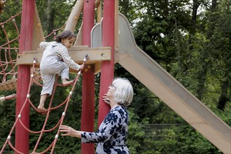 Volunteer. Temporary grandmother with a child in the playground.