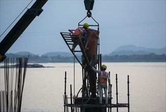 Construction workers busy build pillars of a bridge in the banks of Brahmaputra river on April 3