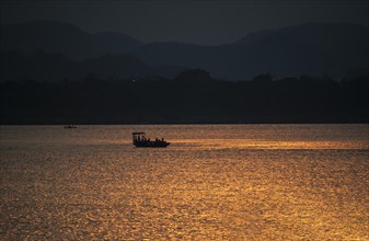 Fishermen row their boat in Brahmaputra river during sunset on April 3