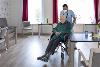 Geriatric nurse pushing a wheelchair in a nursing home