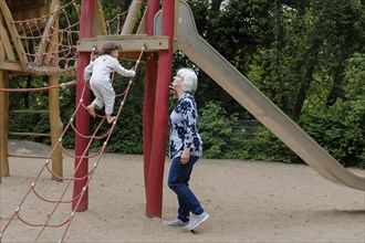 Volunteer. Temporary grandmother with a child in the playground.