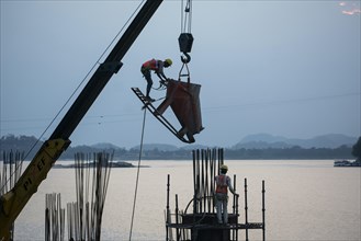 Construction workers busy build pillars of a bridge in the banks of Brahmaputra river on April 3