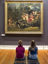 Two children with their backs to the photographer looking at a picture on the wall in the Louvre