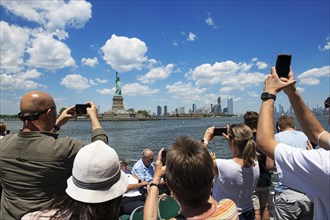 Tourists photographing the Statue of Liberty from the ferry