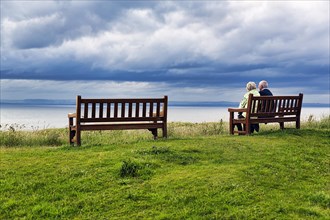 Elderly couple sitting on wooden bench