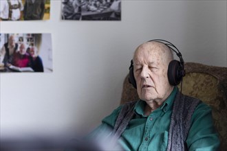 Old man in nursing home listening to music with headphones. Old man in nursing home listening to music with headphones.
