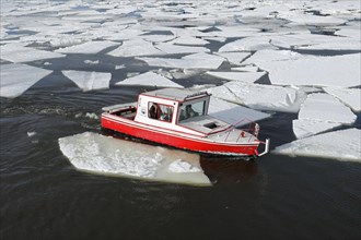 Small red boat between ice sheets