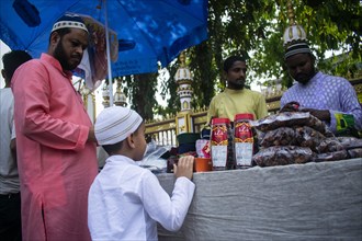 Indian Muslim father buys cap for his son before perform the second Friday prayer in the holy month of Ramadan at a Mosque in Guwahati