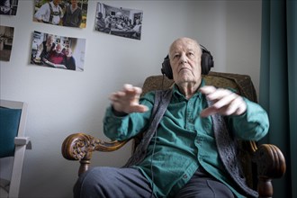 Old man in nursing home conducts to music