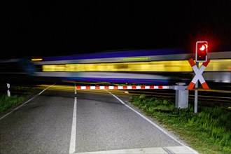 Closed level crossing with passing regional train at night