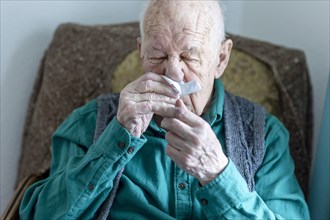 Old man blowing his nose