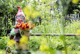 Large garden gnome with flowers in a garden