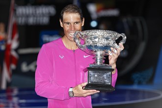 Spanish tennis player Rafael Nadal posing with the championship trophy after winning the mens singles final match of the Australian Open 2022