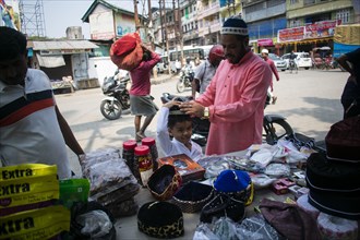 Indian Muslim father buys cap for his son before perform the second Friday prayer in the holy month of Ramadan at a Mosque in Guwahati