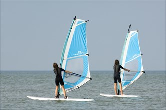 Two young girls windsurfing along the North Sea coast