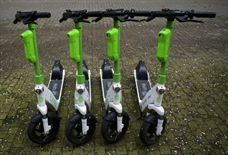 Four parked e-scooters in the bike rental of the company Lime