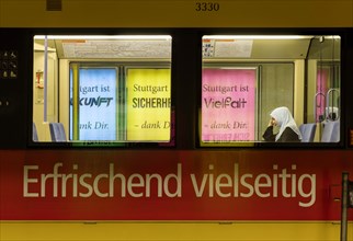 The city advertises diversity on posters. A Muslim woman wearing a headscarf sits on a city tram advertising a diverse product