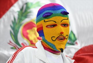 Peruvian fan with mask in front of flag Peru