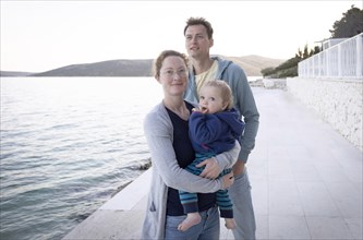 Family with small child standing by the sea