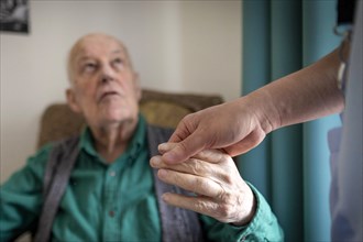 Geriatric nurse holding the hand of an old man in a nursing home