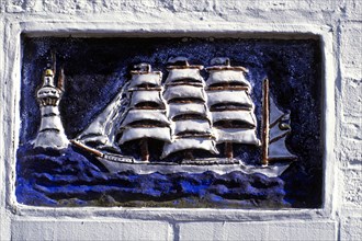 Ceramic relief of a sailing ship and a lighthouse