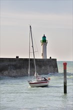 Lighthouse and sailing boat entering the harbour of Saint-Valery-en-Caux
