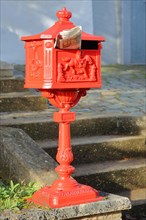 Historic red letterbox with newspaper as mail