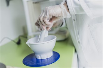 A prescription employee mixes an olive ointment in a fan bowl