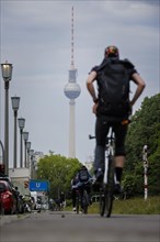 Cyclists ride along Karl Marx Allee on a cycle path towards Mitte. The television tower can be seen in the background. Berlin