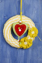 Decorative wreath on blue background and fabric heart