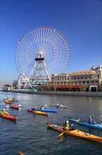 Group of kayaks on excursion and Ferris Wheel Cosmo Clock 21 of Yokohama Cosmo World in background Yokohama city Kanagawa Japan