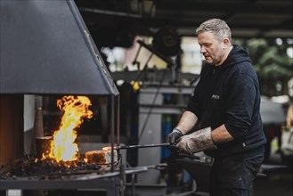A metalworker works at the forge fire
