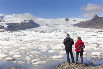 Tourists looking over the glacier lake Fjallsarlon and Icelandic glacier Fjallsjoekull