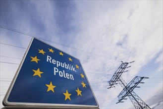 Border sign towards Poland in front of an electricity pylon