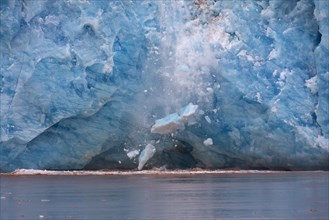 Huge ice chunk breaking from the edge of the Kongsbreen glacier calving into Kongsfjorden