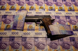 Elegant Semiautomatic 9mm Handgun with Swiss Helvetia Symbol Leaning on Swiss Franc 1000 Banknote in Switzerland