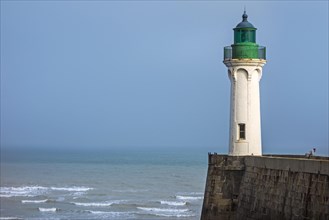 Lighthouse and lonely man looking at sea from pier in the harbour at Saint-Valery-en-Caux
