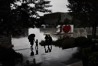 People with umbrellas stand out during a rainstorm in Tirana