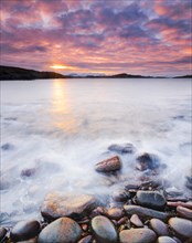 Atmospheric coloured cloudy sky at sunrise on a rocky beach near Reiff on the west coast of Scotland