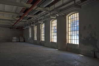 Large windows in a vacant farbrik hall of a former paper factory