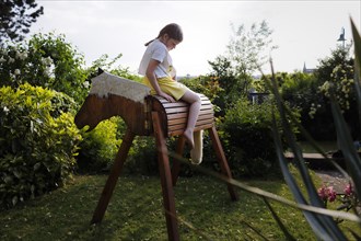 Girl sitting sadly on a wooden horse