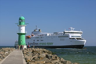 Lighthouse on harbour mole and hybrid ferry MV Berlin from Scandlines entering the port at Warnemuende