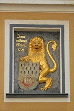 Golden lion figure with coat of arms and inscription Gasthaus zum goldenen Loewen and year 1709
