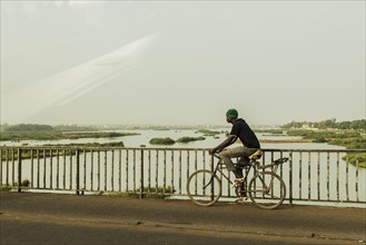 A man drives across a bridge over the Niger River in Bamako