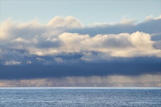 Low-lying rain clouds drift over the open waters of the blue Atlantic Ocean
