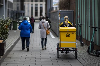 A postwoman drives past passers-by. Berlin